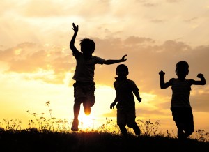 Children running on meadow at sunset