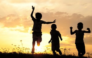 Children running on meadow at sunset